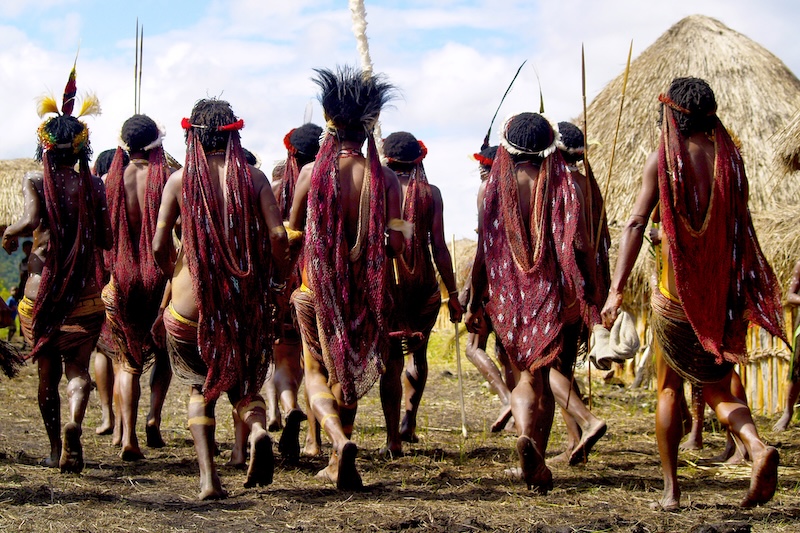 Participants in traditional attire gather for a cultural ceremony in a rural village setting Papua  New Guinea
