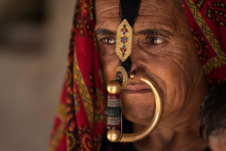 Close-up portrait of a Jat woman in Gujarat wearing traditional gold nose ring and forehead jewelry