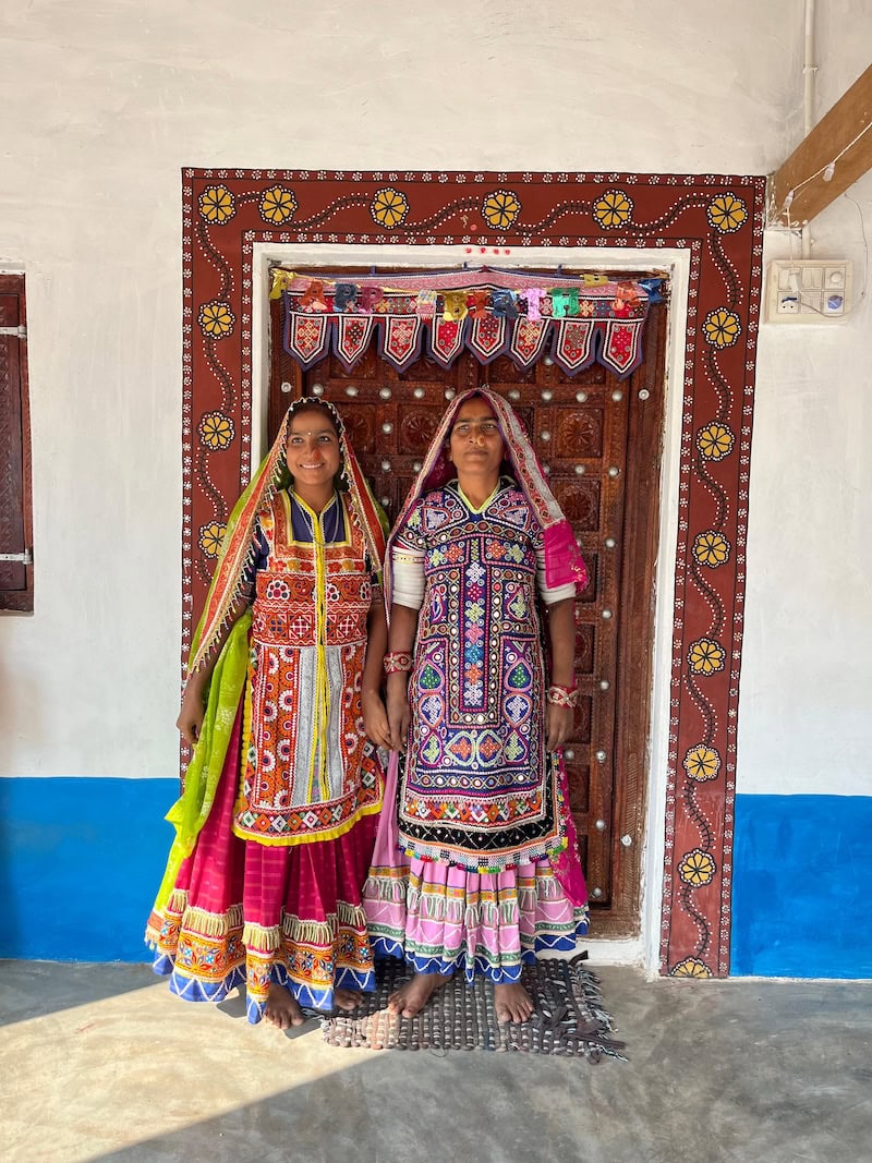 Women in vibrant traditional Gujarati dress standing at an ornate doorway