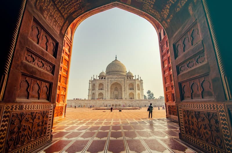 Taj Mahal framed through a red sandstone archway at sunrise in Agra, India